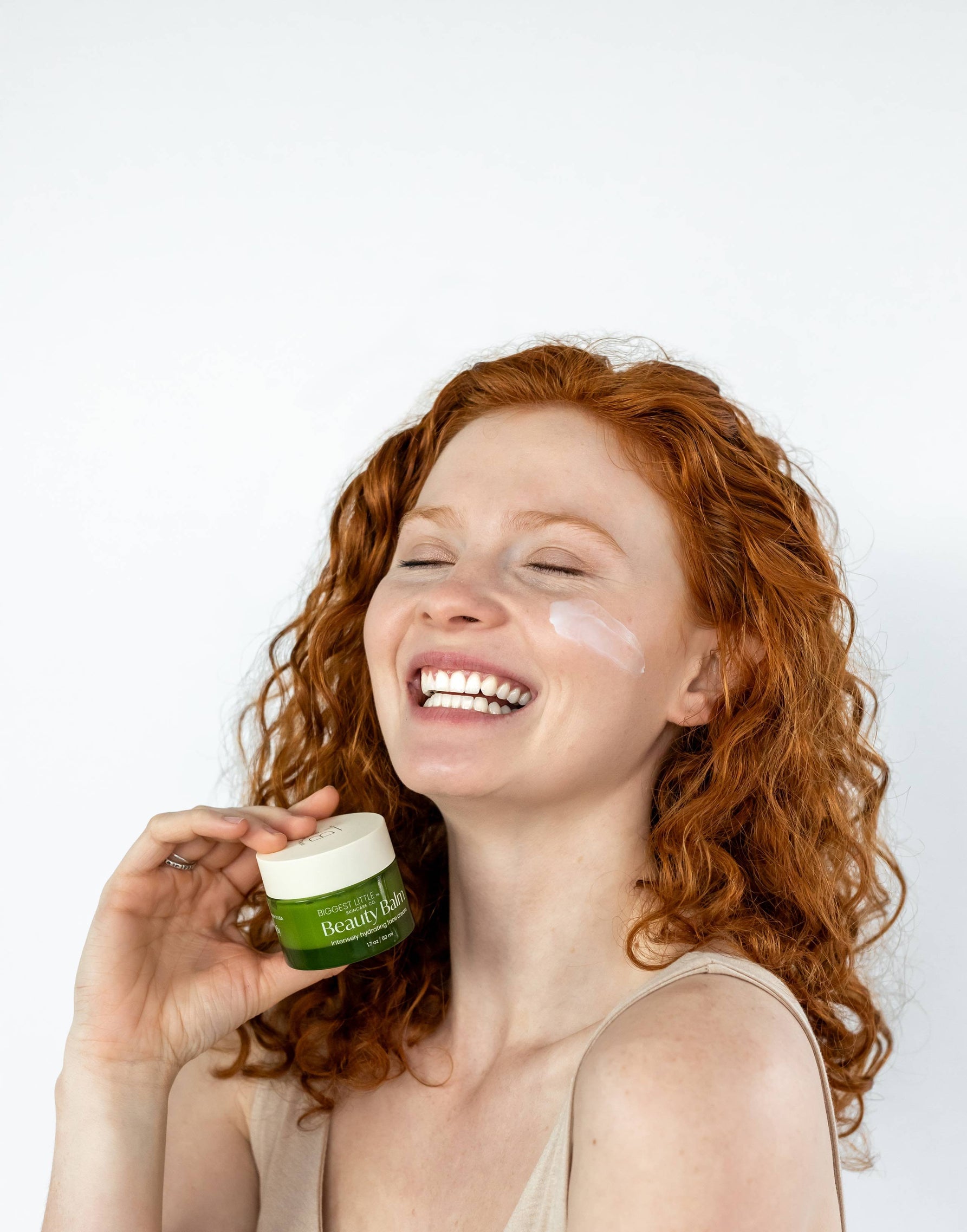 red head young woman smiling while holding the Beauty Balm on her hand